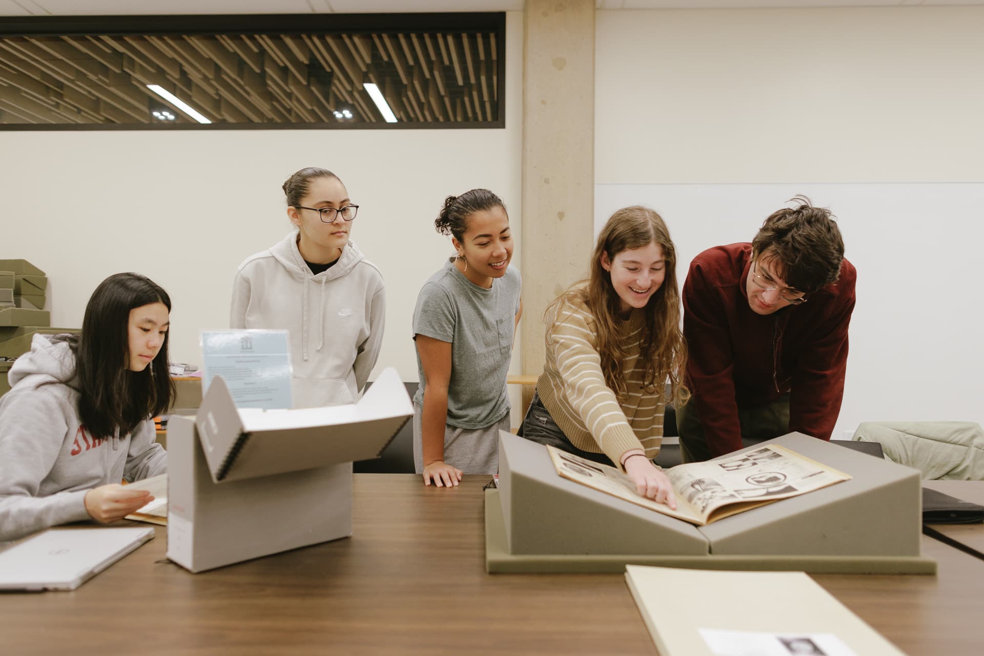 Students gathered around archival materials in a classroom.
